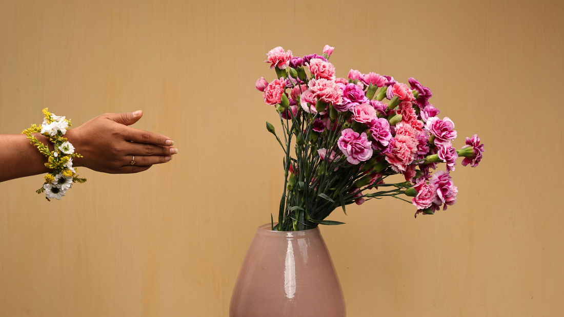 Hand selecting vibrant pink carnations arranged in a pastel vase, highlighting the art of choosing fresh flowers for decor and special moments.