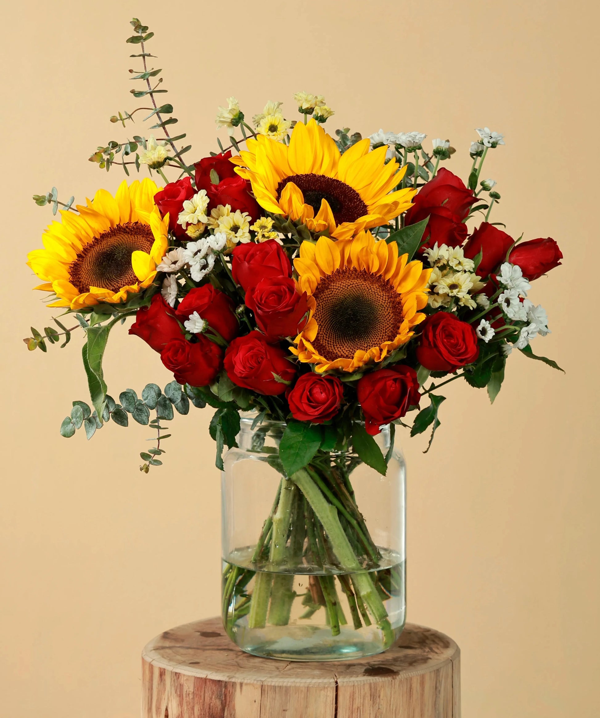 Vibrant bouquet of sunflowers and red roses in a glass vase