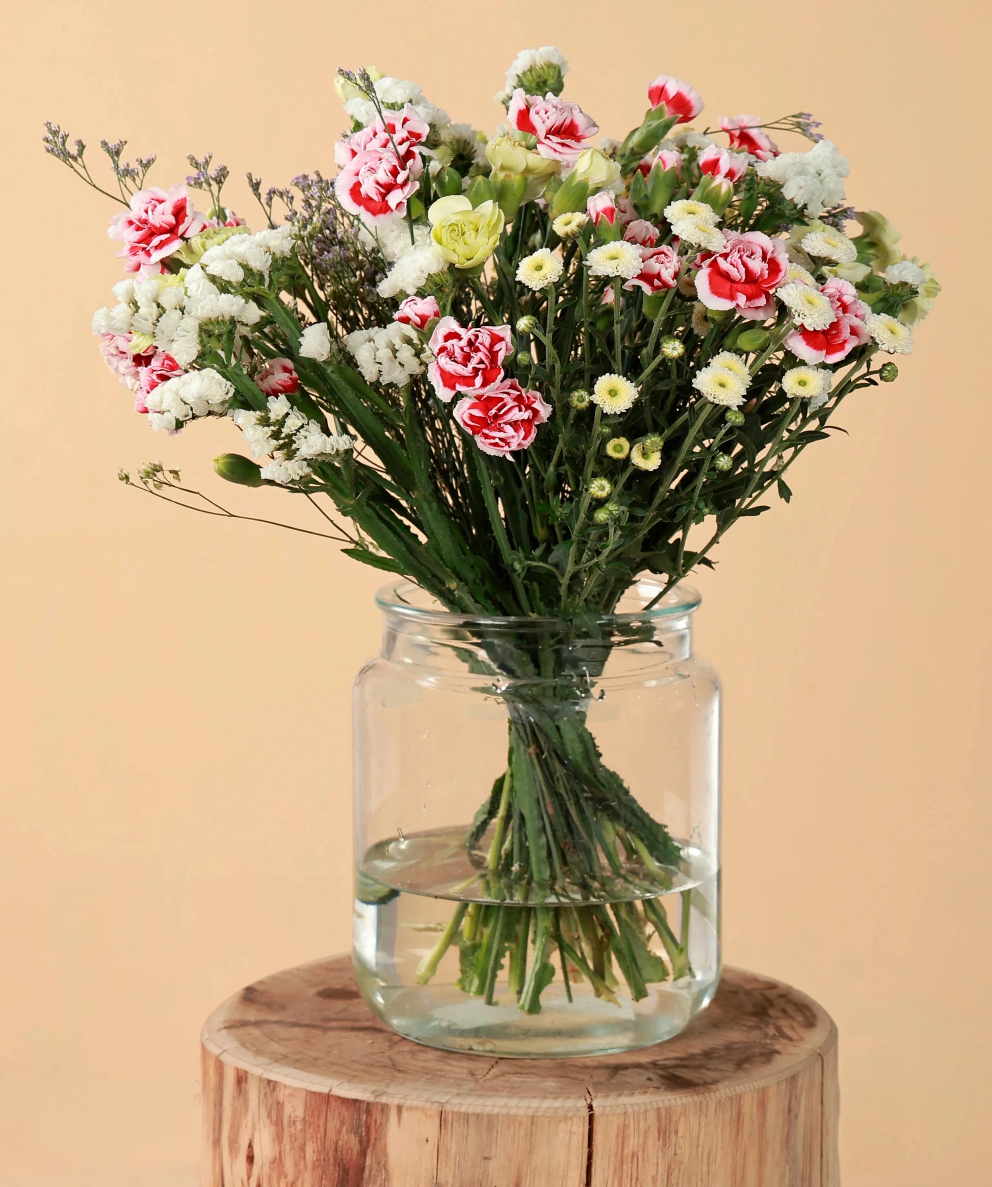 Mixed flower arrangement with carnations, baby's breath, and other blooms in a glass vase